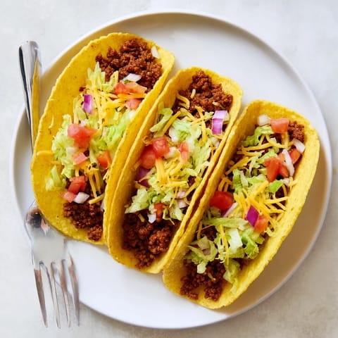 American-Style Tacos stuffed with lettuce, tomatoes, and cheddar, ready for a family weeknight dinner.