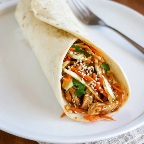 Golden teriyaki chicken strips shine on a soft tortilla layered with crisp cabbage and carrots in this Teriyaki Chicken Wrap.