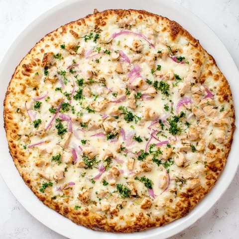 Sliced Chicken Alfredo Pizza reveals layers of gooey cheese, savory chicken, and Alfredo sauce on a crisp, golden crust.