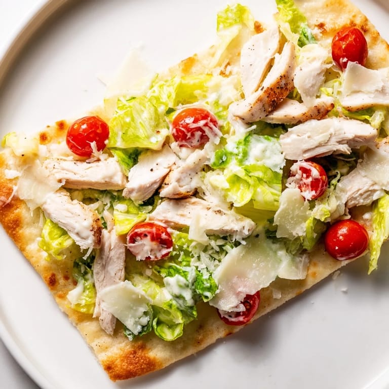 Freshly grated Parmesan and cherry tomatoes top this Caesar Chicken Flatbread, served on a rustic wooden board.