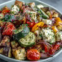 Roasted Mediterranean Greek Vegetables fresh from the oven, with caramelized cherry tomatoes and red onion on a baking sheet.