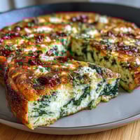 A golden, fluffy spinach and feta frittata studded with vibrant sun-dried tomatoes and fresh herbs.  